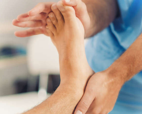 Physiotherapist doing healing treatment on patient foot. Therapist wearing blue uniform. Osteopathy, Chiropractic foot adjustment
